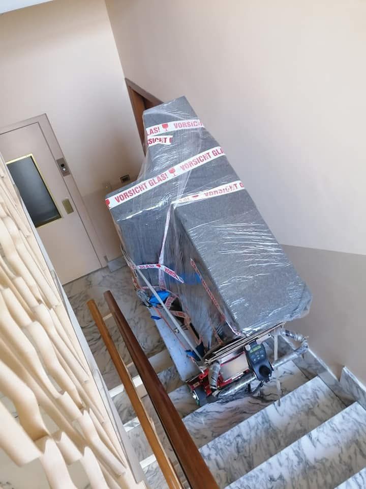 Mobili imballati vengono trasportati su per una tromba delle scale, coperti da plastica trasparente e cinghie blu.