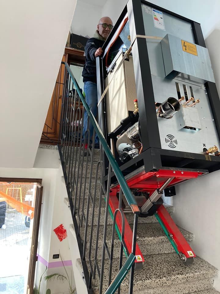Un operaio manovra un grosso macchinario su per una scala nel corridoio di un edificio interno.