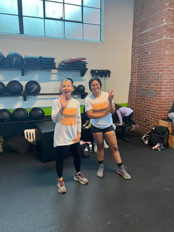 Two women are standing next to each other in a gym.