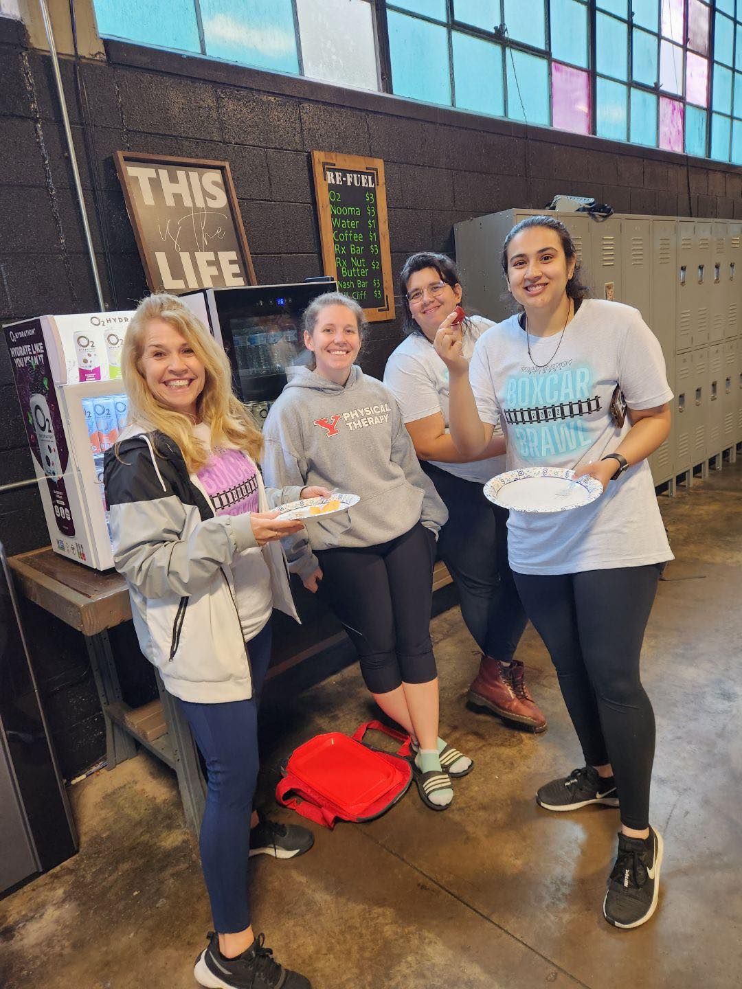 A group of women are standing next to each other holding plates of food.