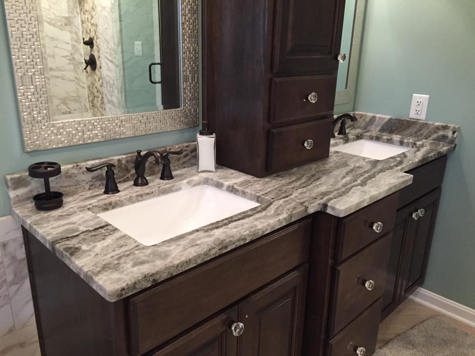 Bathroom with dark wood cabinets, marble countertops, and two sinks.