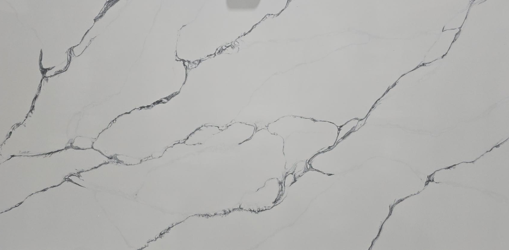 Large white marble-look slab with gray veining, hanging in a workshop by a clamp at the top center.