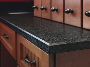 Black granite kitchen countertop with wooden cabinets and black knobs