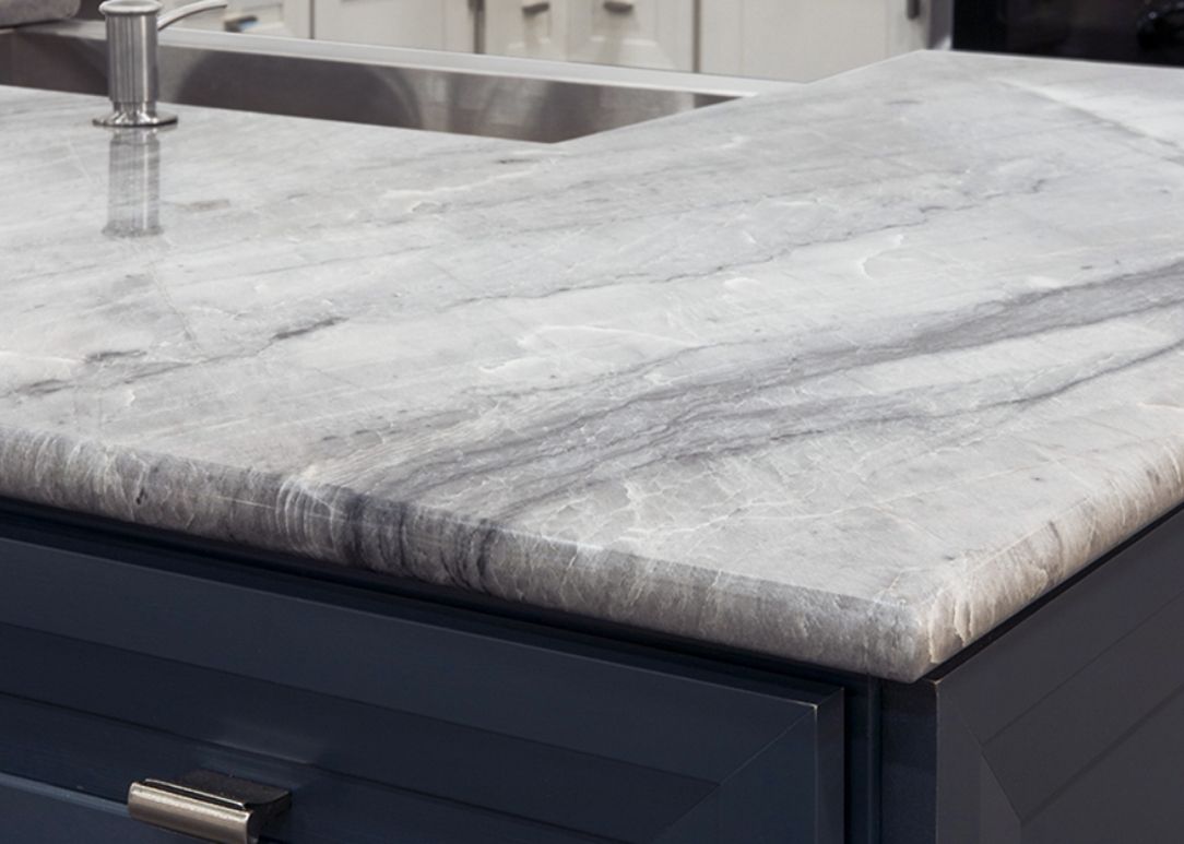 Light gray marble kitchen countertop with an integrated sink and dark cabinet below