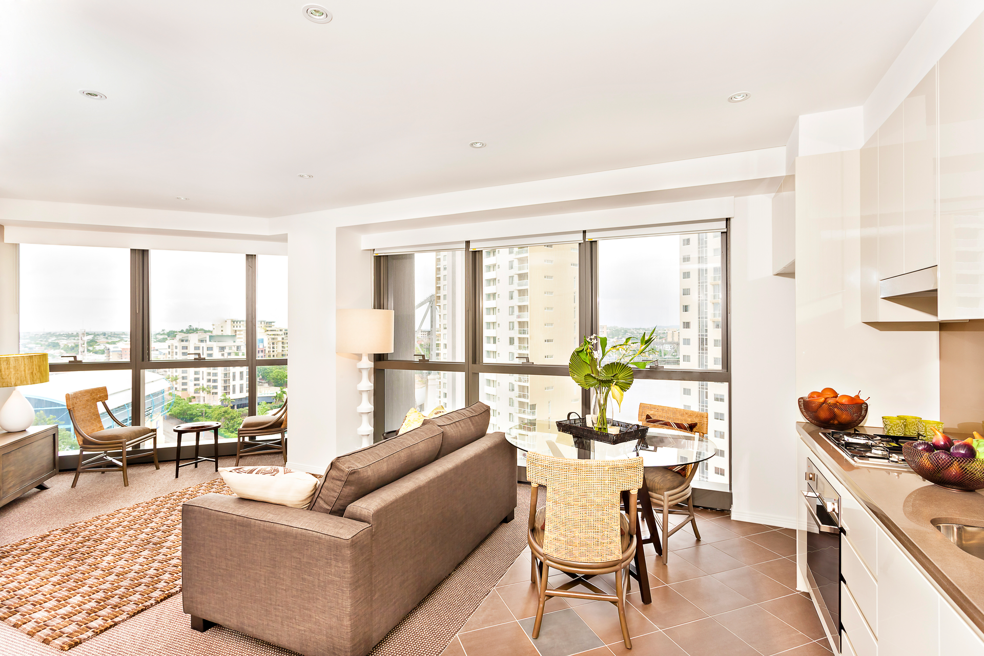 Modern apartment interior with living and dining areas, large windows, and city views.
