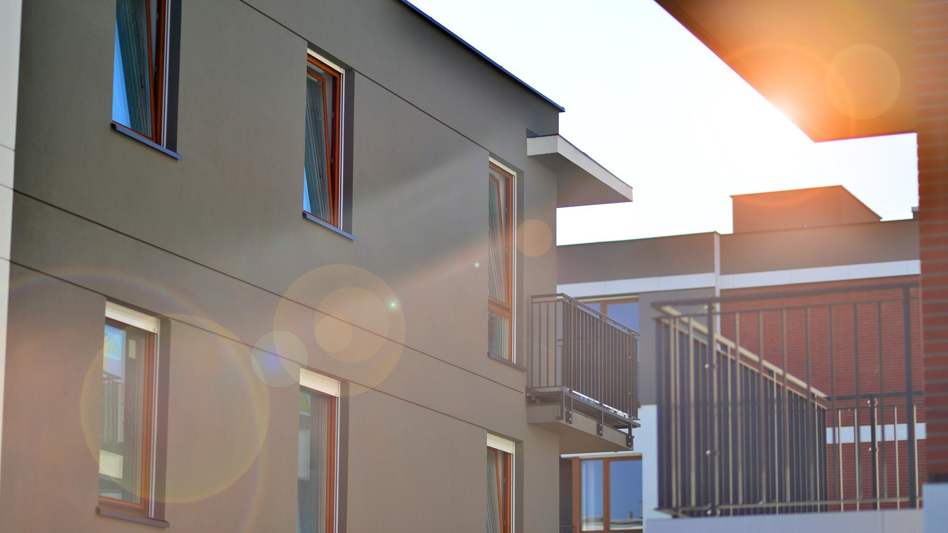 Modern apartment building exterior with balcony and bright sunlight.