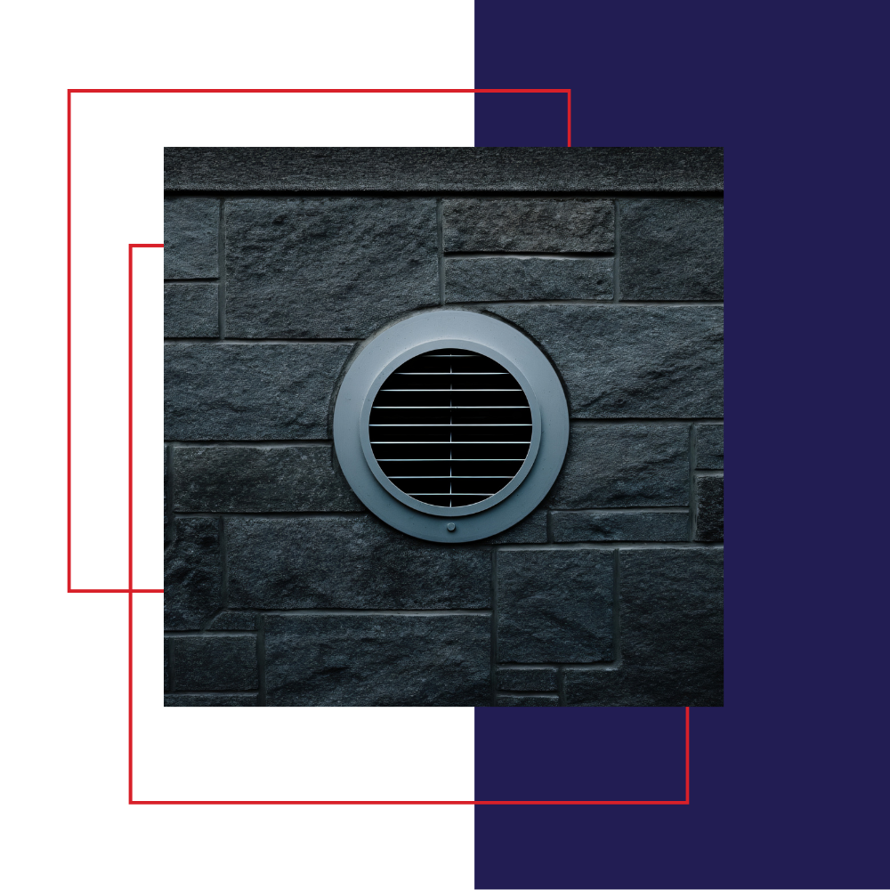 Round vent cover in a dark stone wall, with a white and blue geometric background.
