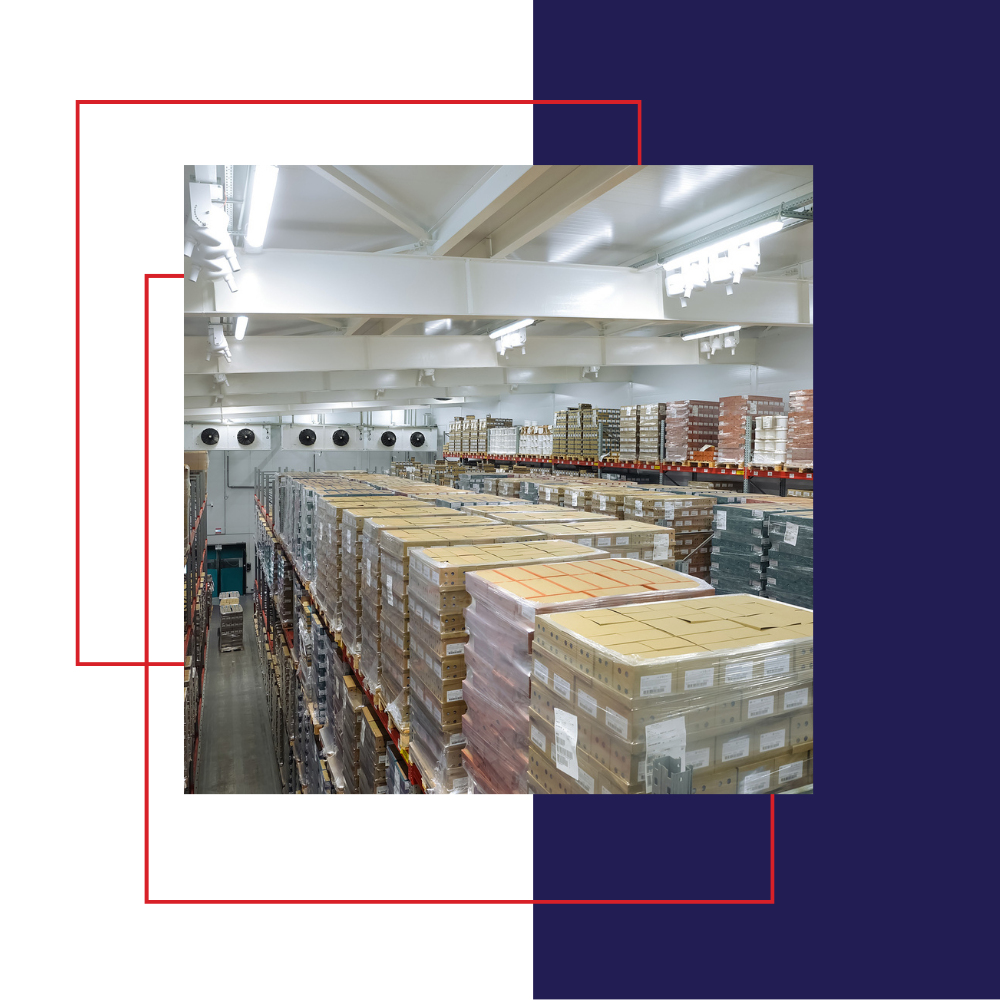 Inside a warehouse, pallets of boxes on shelves under bright lights.
