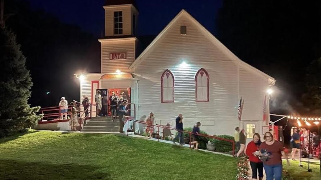 A group of people are standing in front of a church at night.