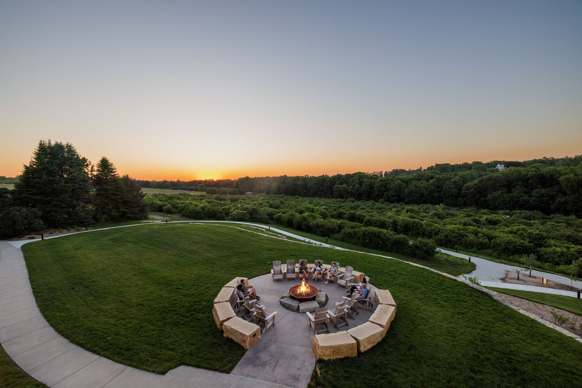A fire pit in the middle of a grassy field at sunset