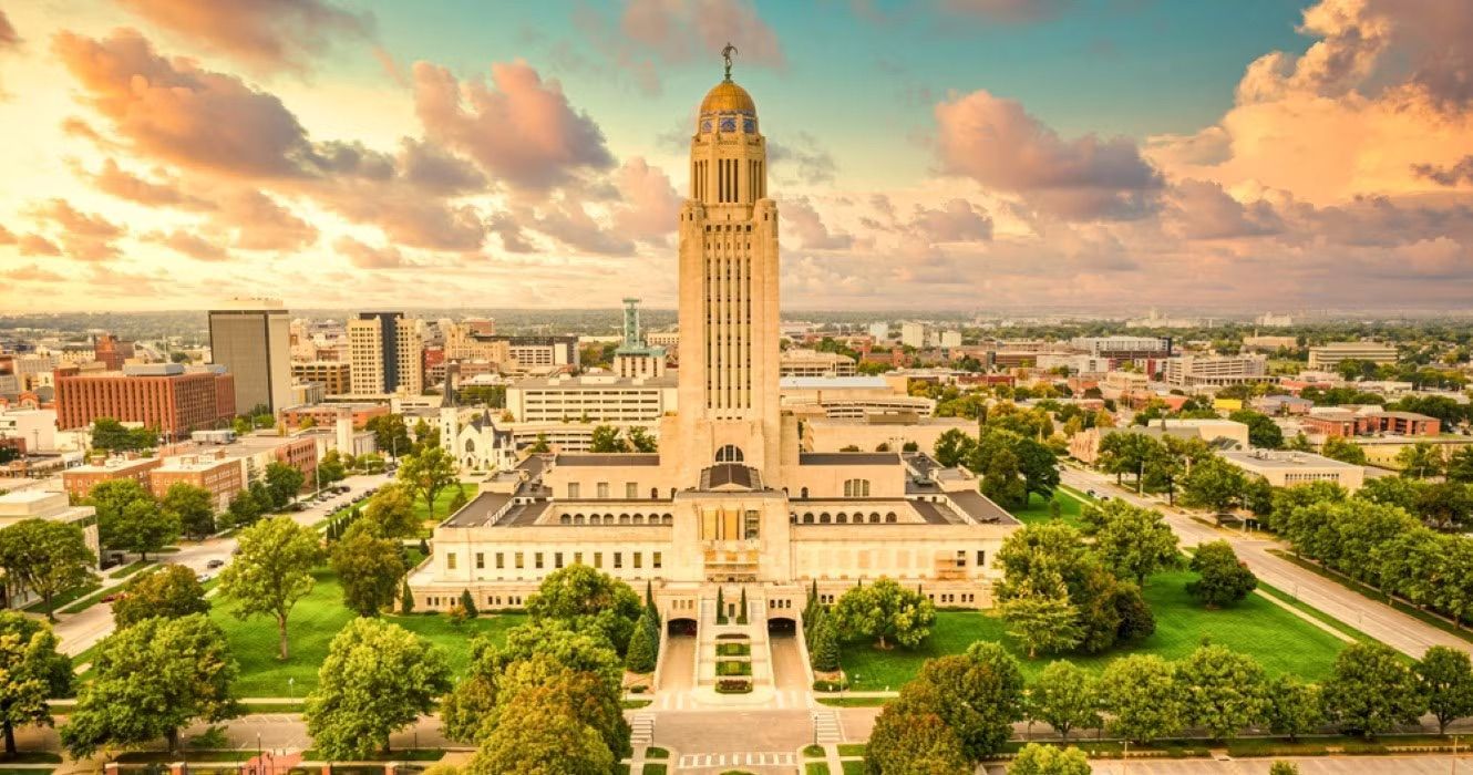 An aerial view of a large building with a clock tower in the middle of a city.