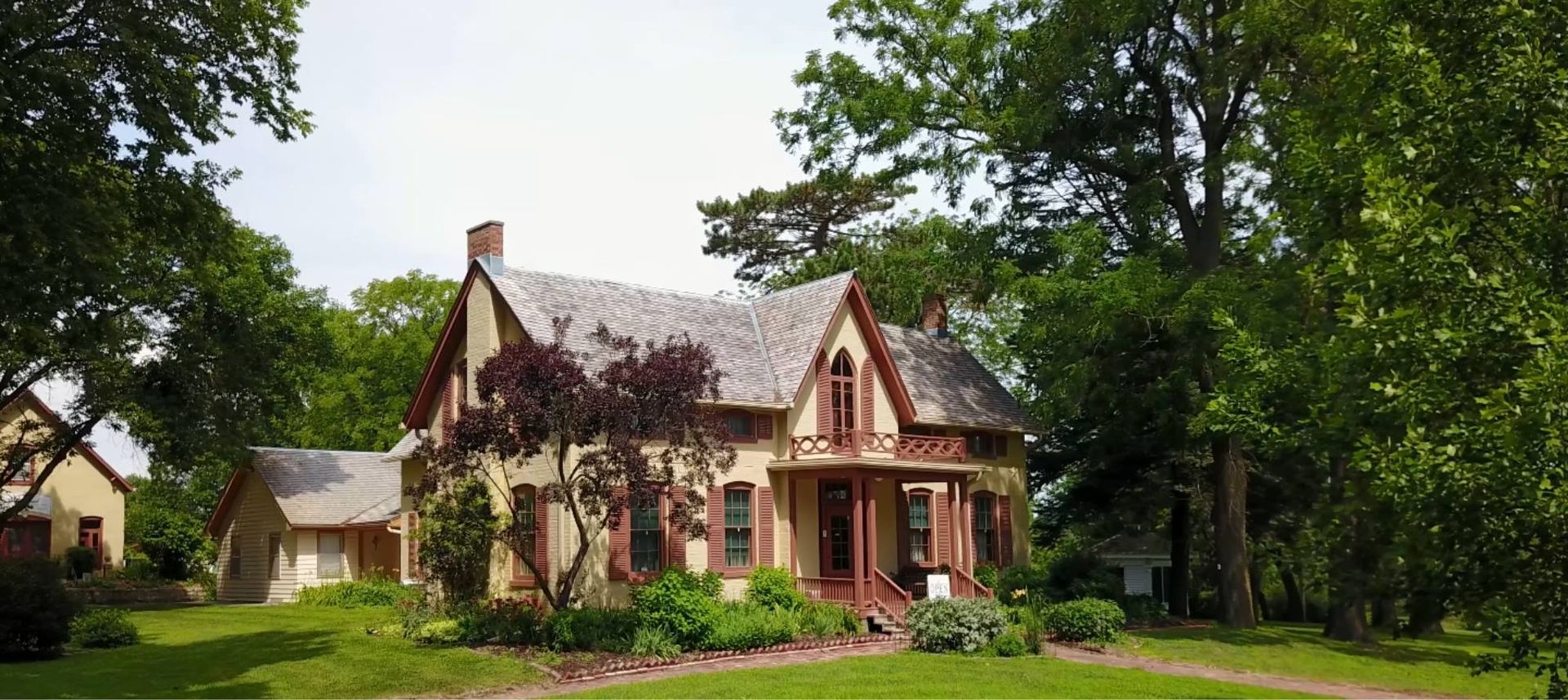 A large house is surrounded by trees on a lush green hillside.
