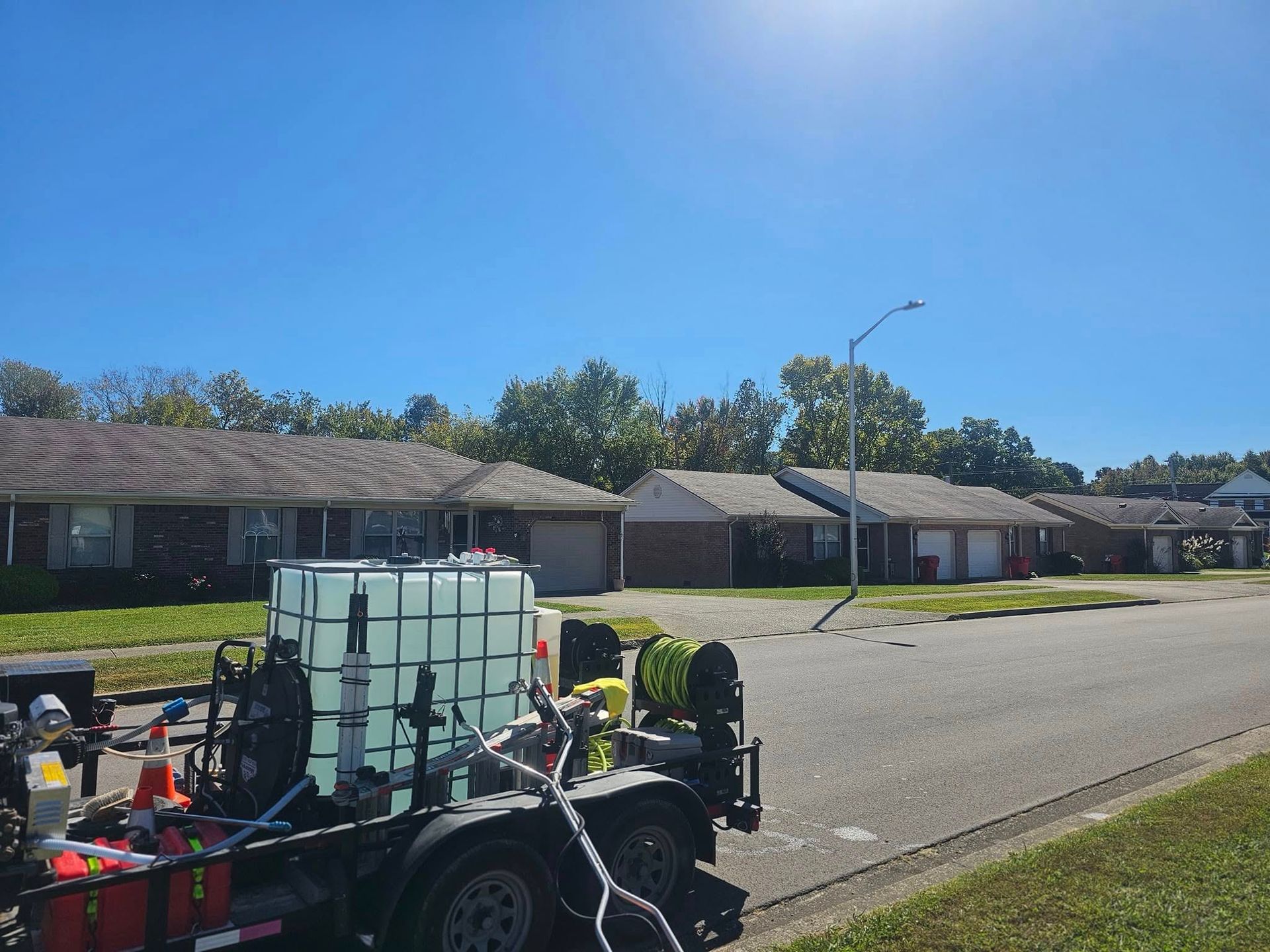 Utility cart loaded with gear parked on a sunny residential street near single-story houses