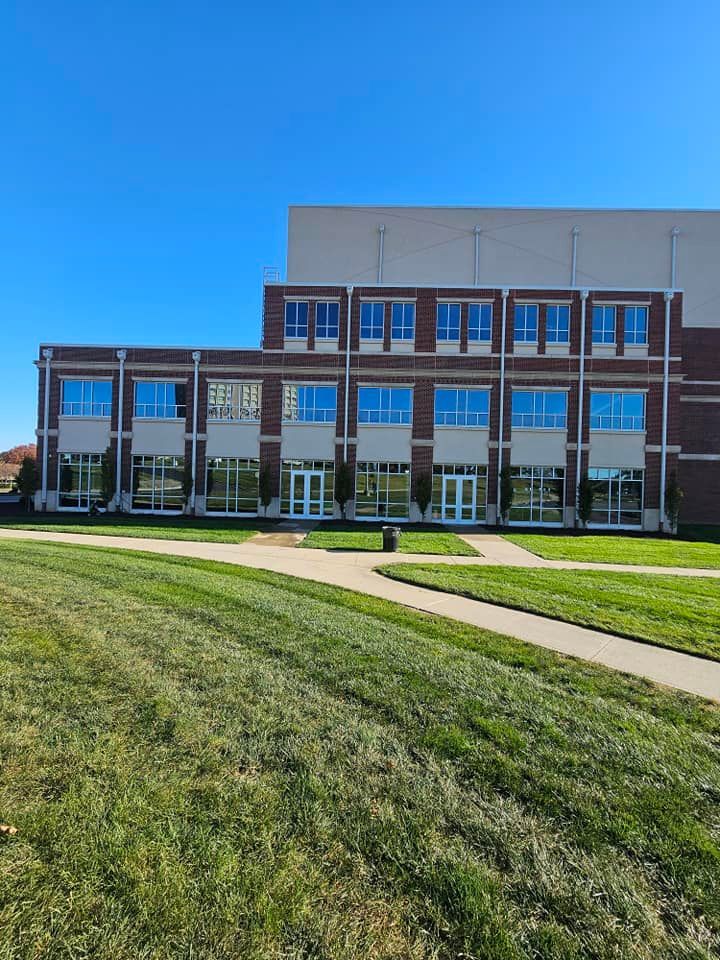 Modern brick-and-glass building with a grassy lawn and clear blue sky