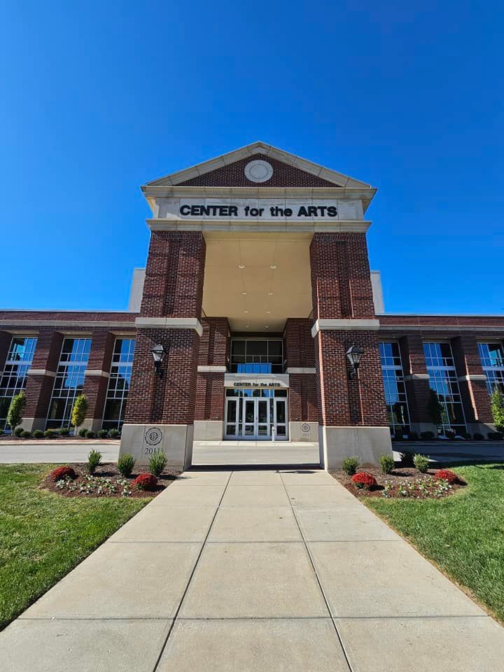 Brick Center for the Arts building with a columned entrance under a blue sky.