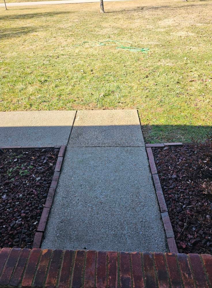 Front walkway leading to a grassy yard, bordered by brick and dark mulch beds