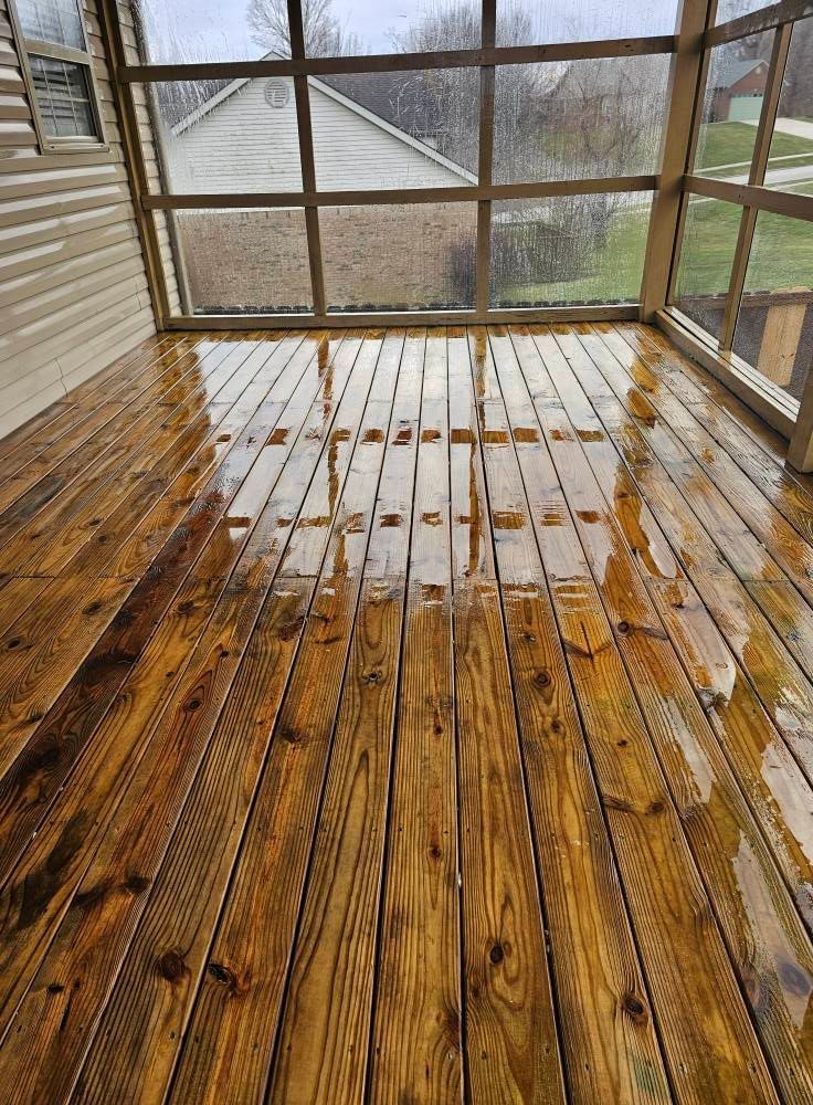 Rain-soaked wooden porch with screened walls and a view of a road outside