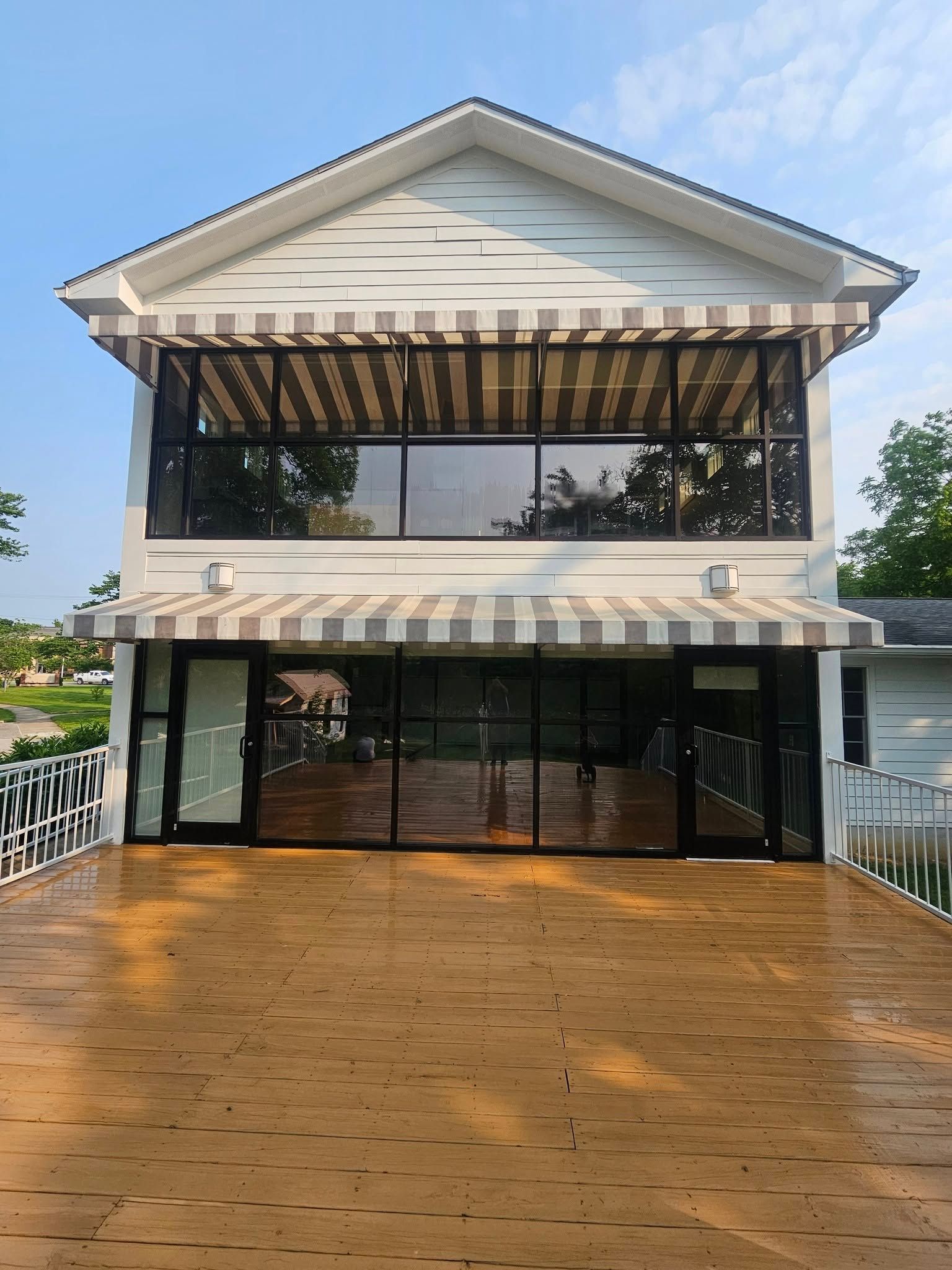 Two-story white house with a large wooden deck and black glass doors