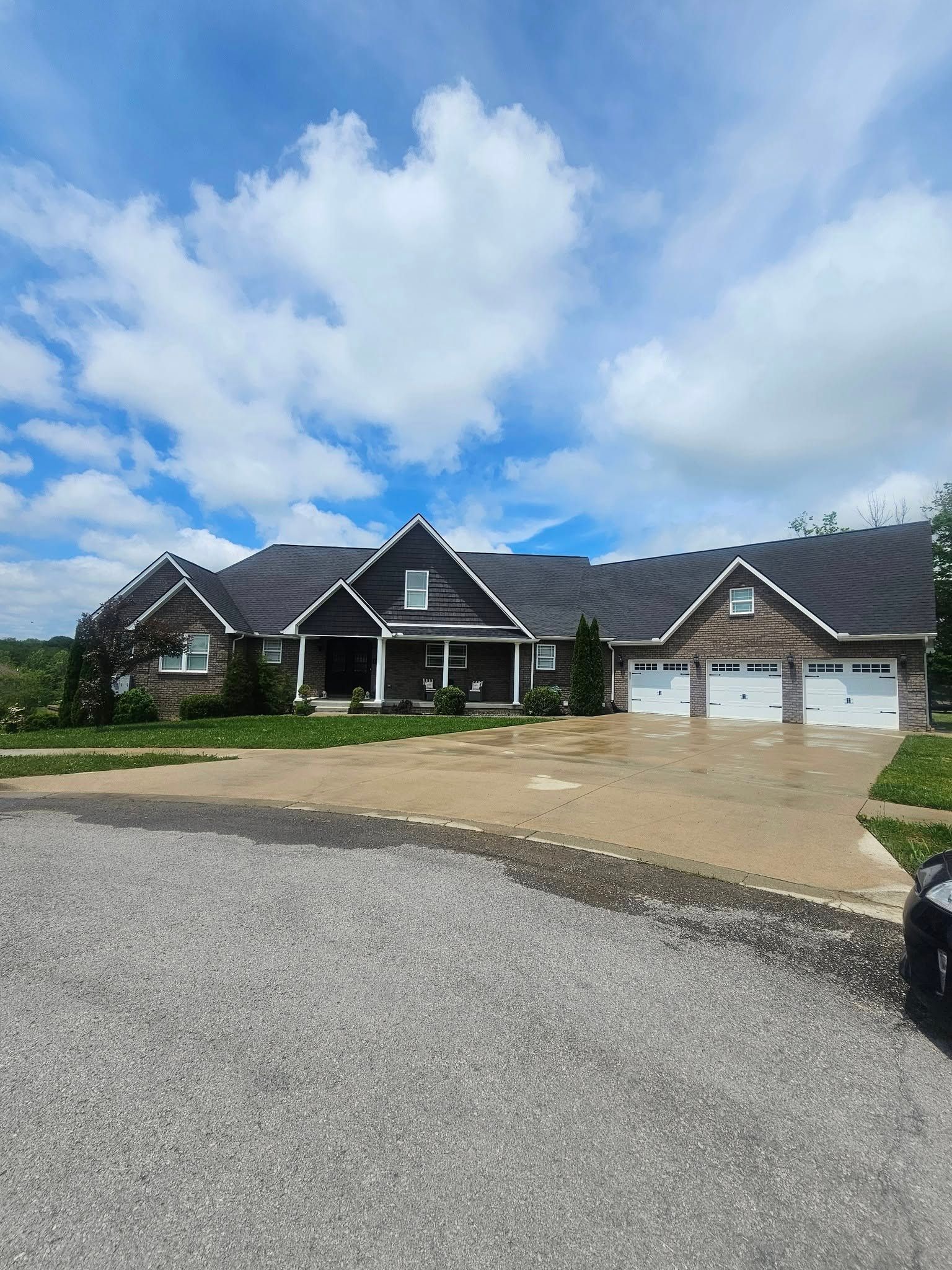 Suburban brick house with a gravel driveway and partly cloudy blue sky