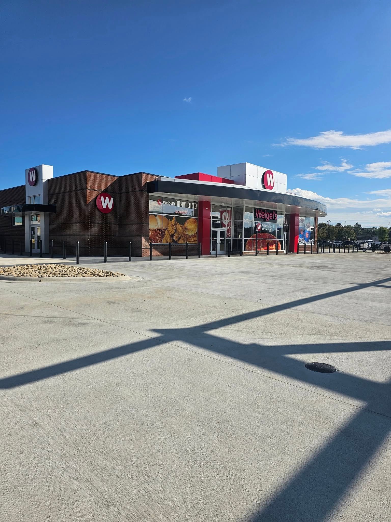Convenience store and gas station on a sunny day with a wide gravel lot and blue sky