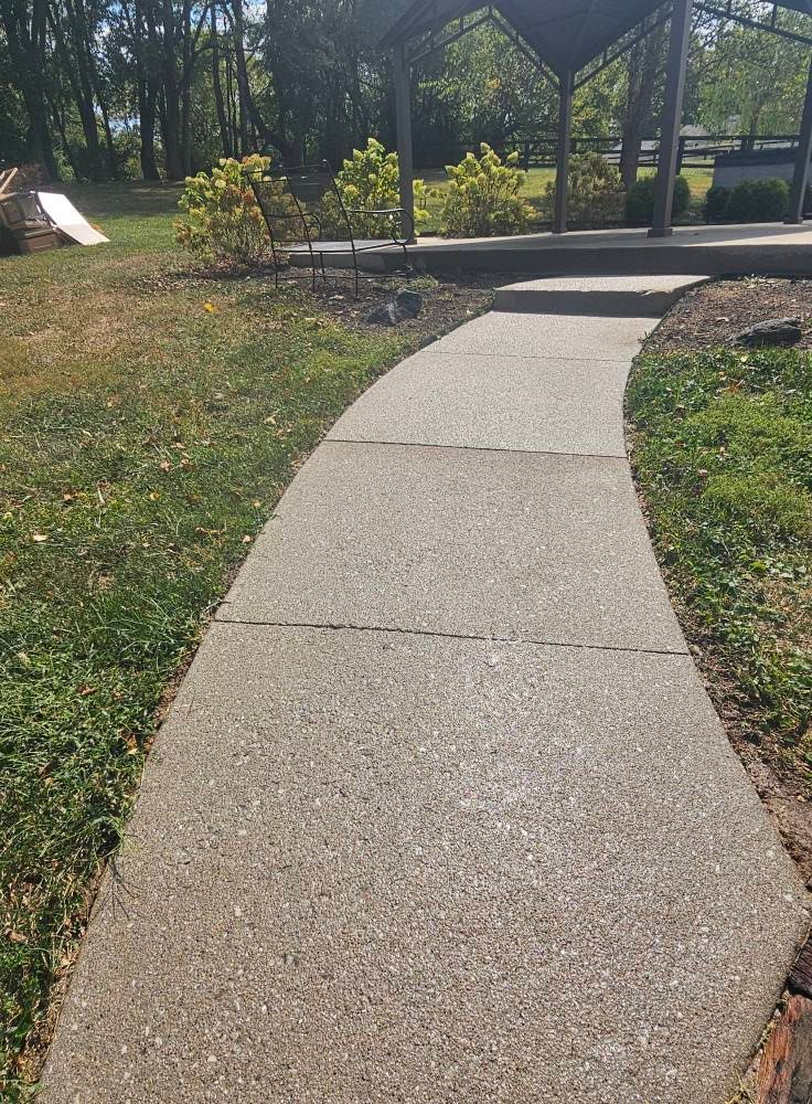 Curved concrete walkway leading to a park gazebo on a sunny day