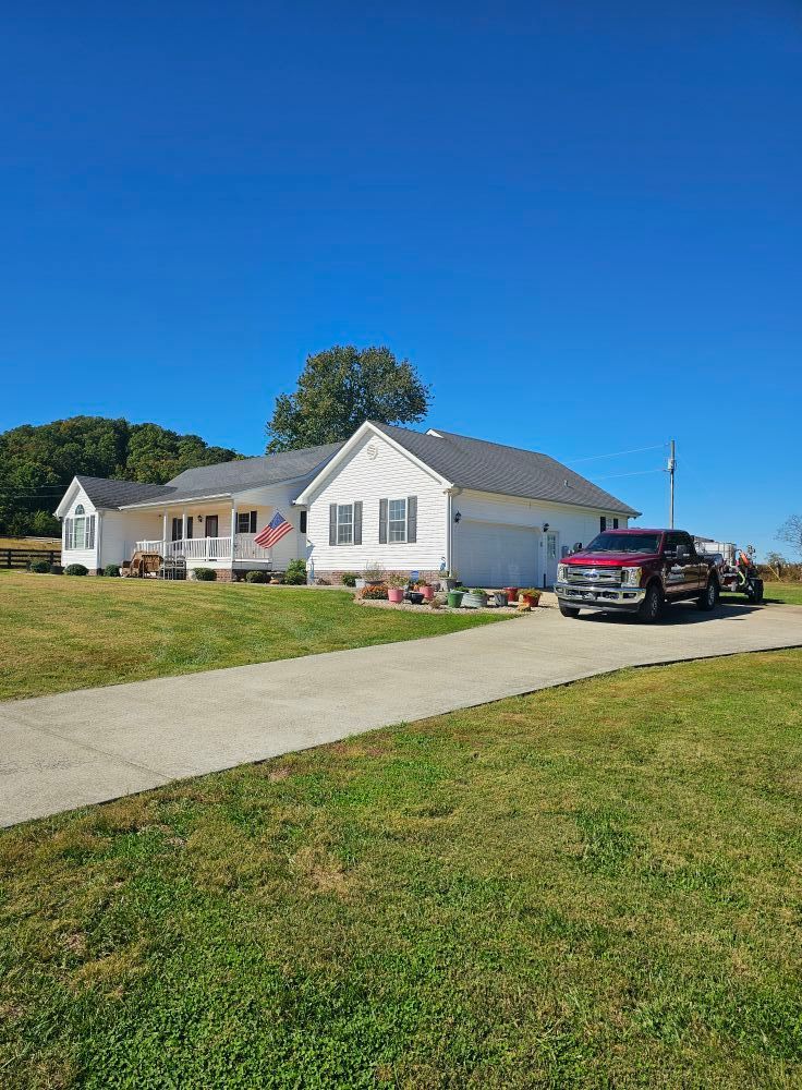 White single-story house with a porch, red pickup truck, and green lawn under a clear blue sky