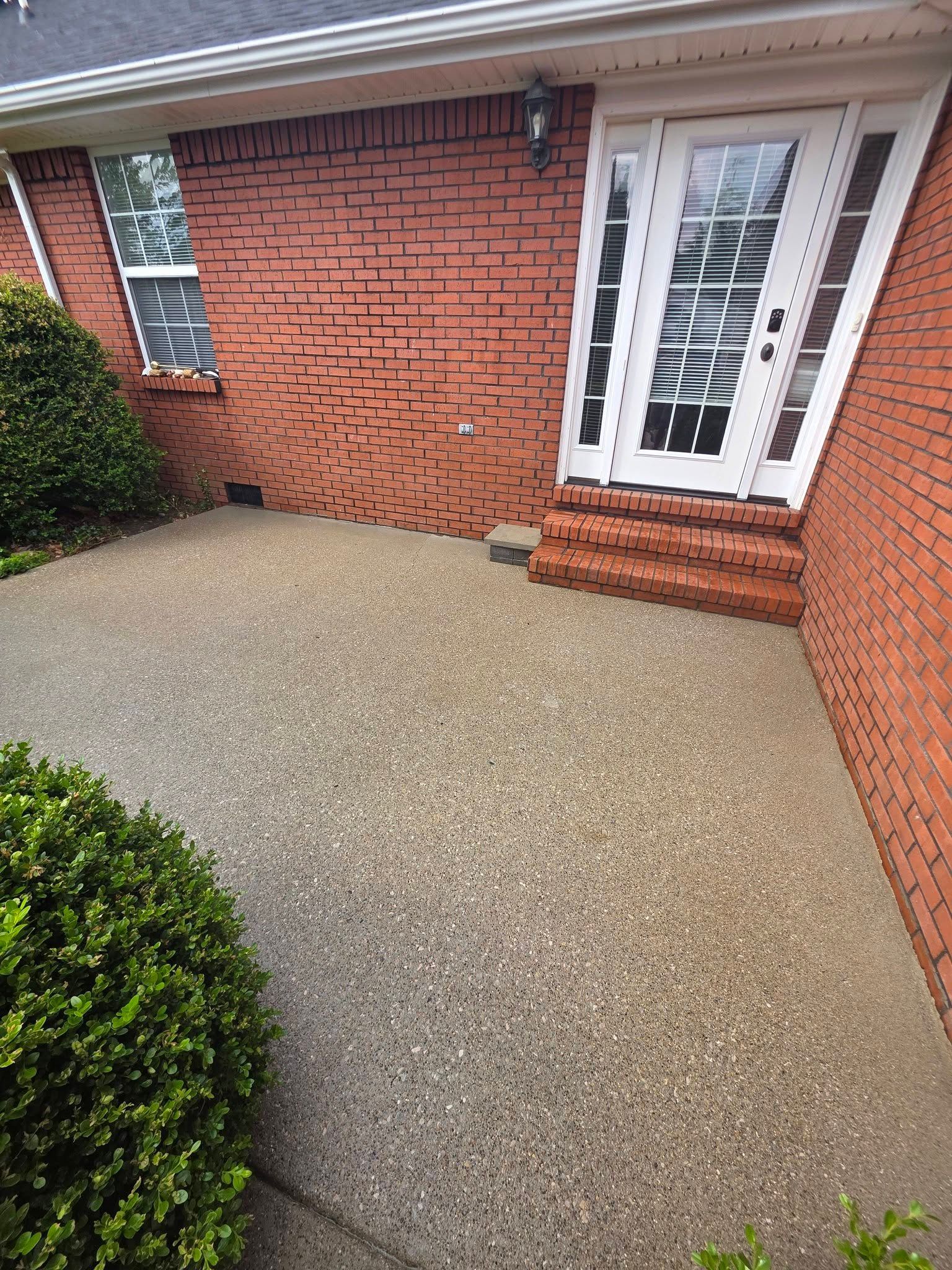 Front patio with red brick wall, white front door, and textured concrete surface