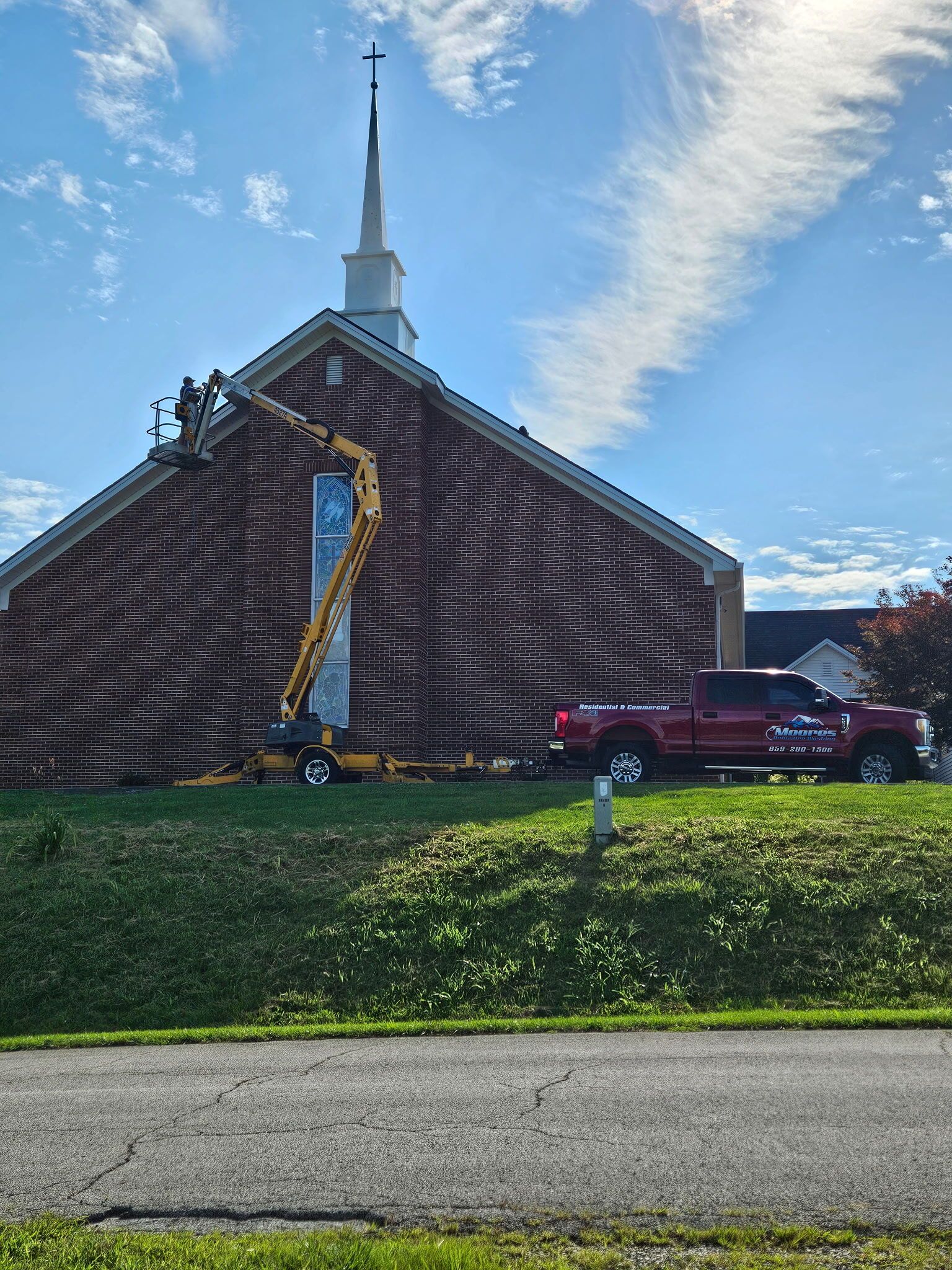Church roof under repair with crane and workers on a sunny day