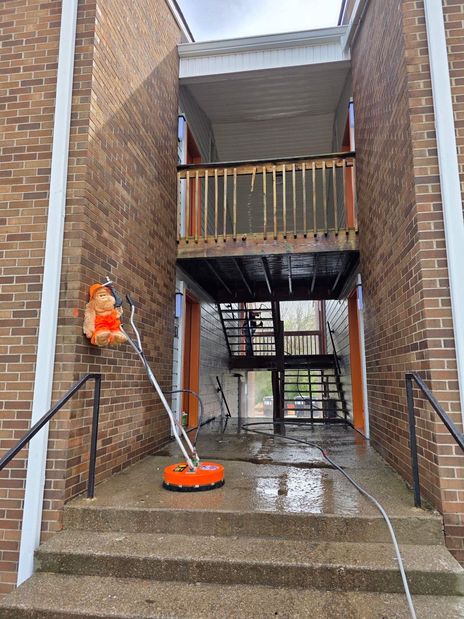 Power washing a wet brick stairwell and covered walkway in an apartment complex