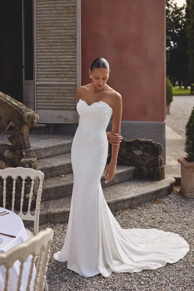 Woman in a white strapless mermaid wedding dress poses on steps.