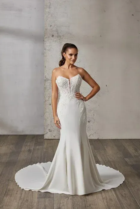 Woman in white strapless mermaid wedding dress, posing with hand on hip.