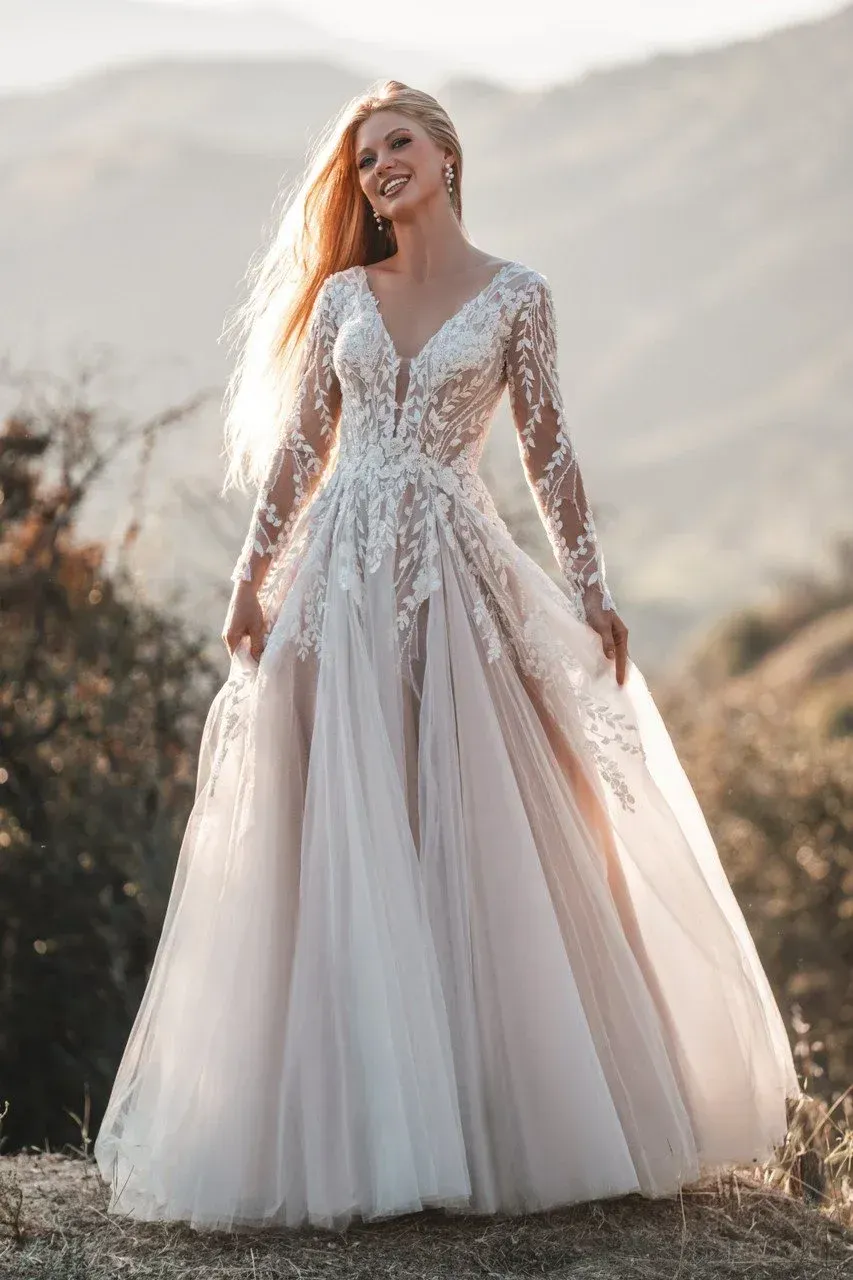 Blonde woman in a white wedding dress, smiling, with long flowing hair. Outdoors, natural light.