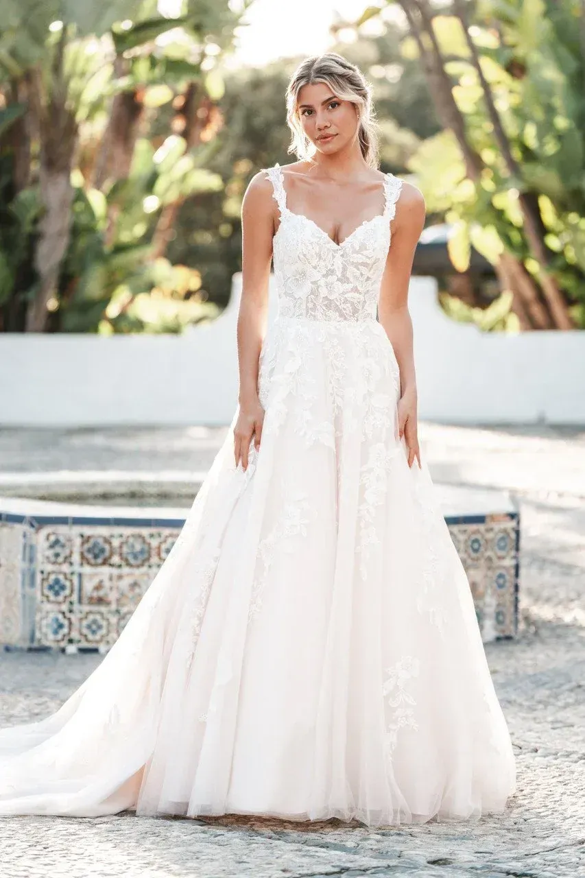 Woman in a wedding dress, posing outdoors near a fountain.