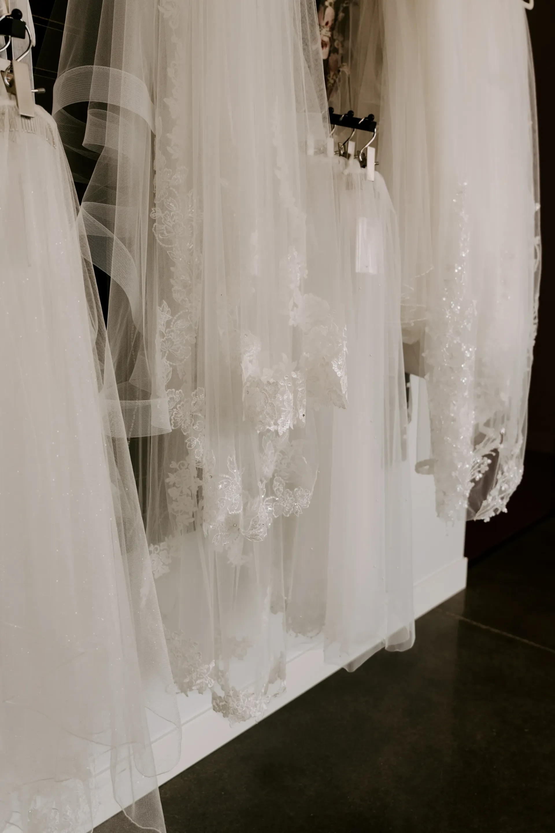 White bridal veils with lace trim hang on display.
