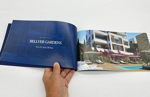 Una persona sostiene un libro azul con la imagen de un edificio y una piscina.