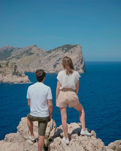 Un hombre y una mujer están sentados encima de una roca con vistas al océano.