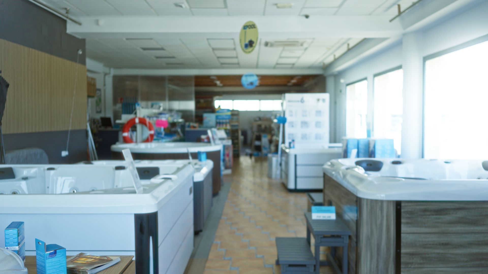 Spacious showroom displaying hot tubs and spa units arranged in rows under bright lighting. Spacious showroom displaying hot tubs and spa units arranged in rows under bright lighting.