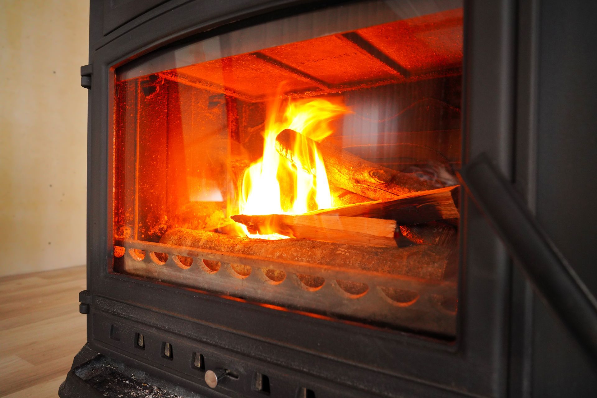 Wood-burning stove with burning logs visible through glass, flames glowing brightly inside. Wood-burning stove with burning logs visible through glass, flames glowing brightly inside.
