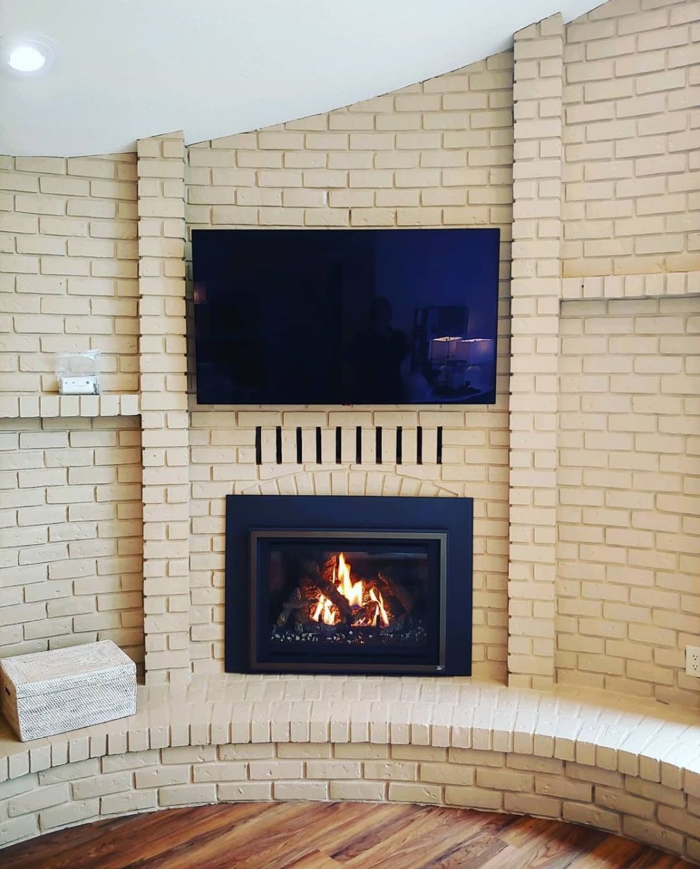 Brick fireplace with lit fire, flat-screen TV above, and curved built-in bench seating.