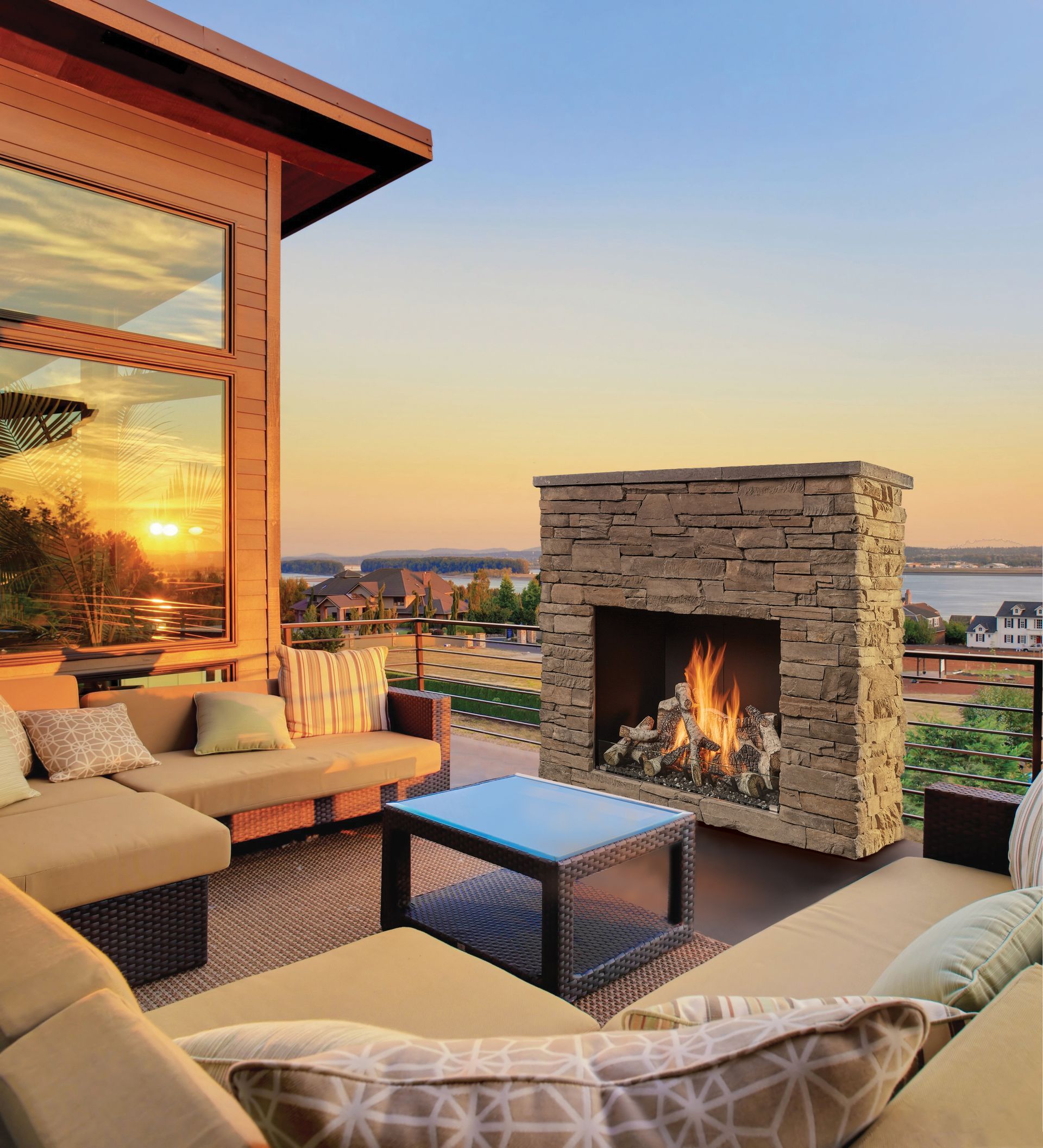 Cozy rooftop patio with stone fireplace, wicker seating, and sunset city views