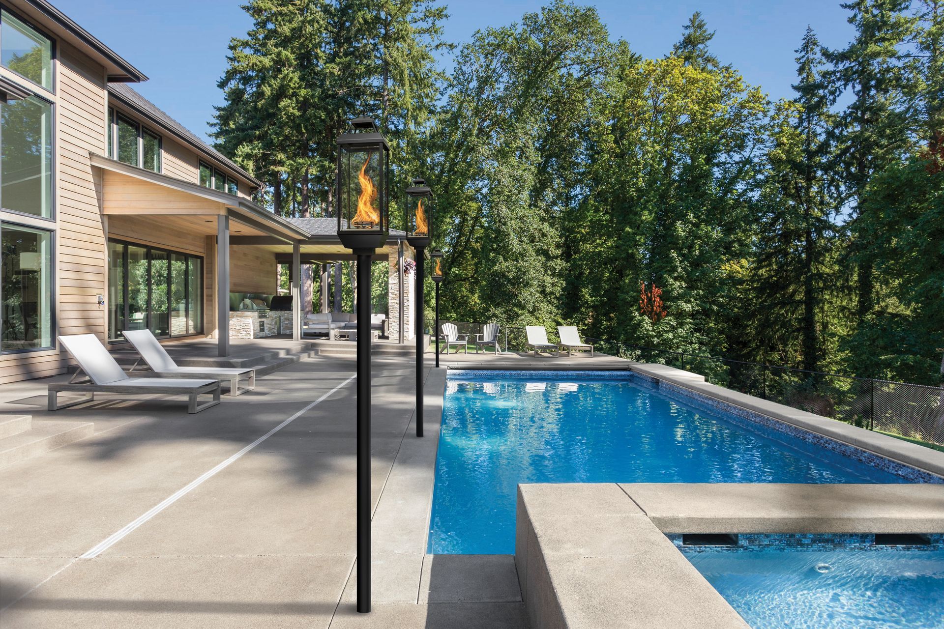Modern house patio with lounge chairs beside a blue swimming pool and trees in the background