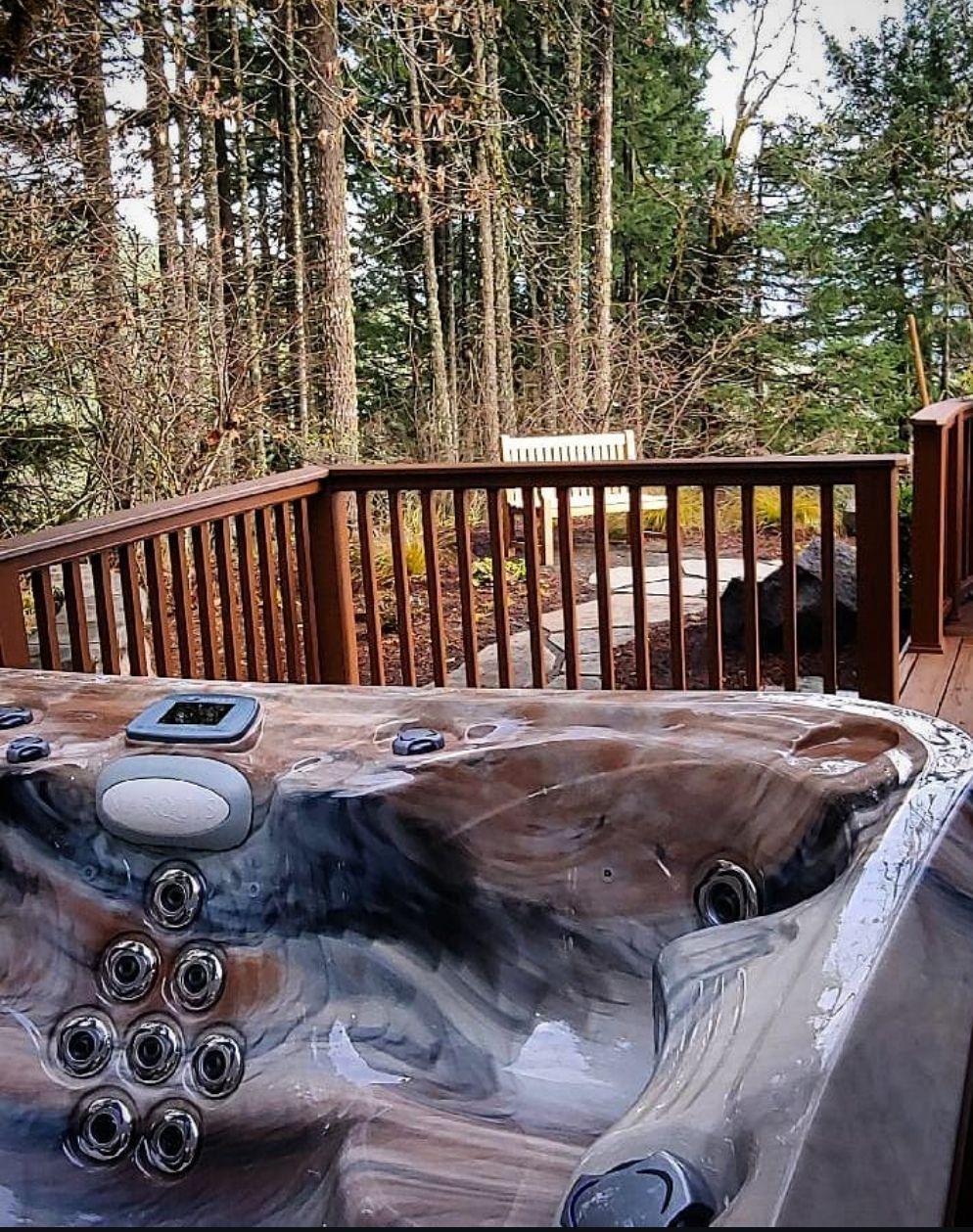 Wooden deck with a hot tub overlooking a forest of tall trees