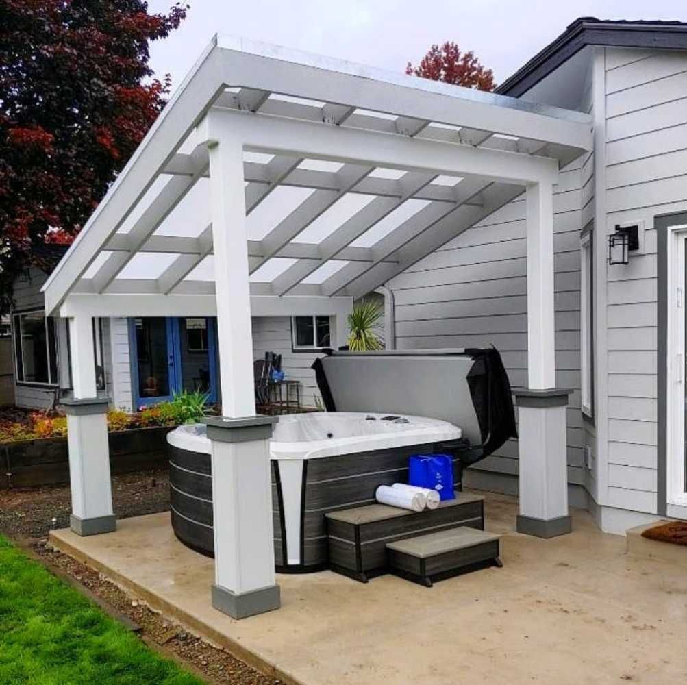Covered backyard hot tub area with a white pergola-style roof attached to a house.