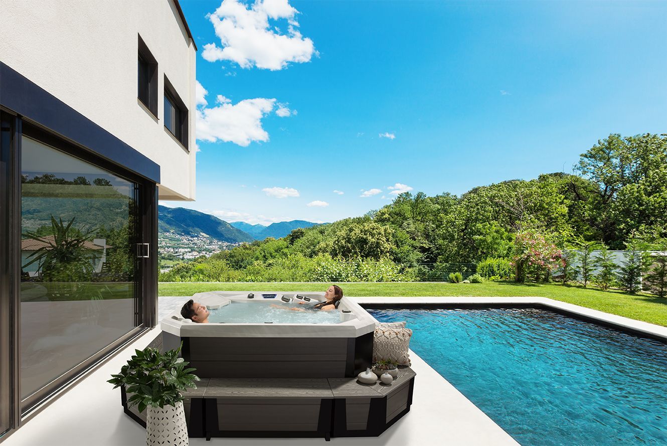 Scenic view of couple in hot tub outside near pool