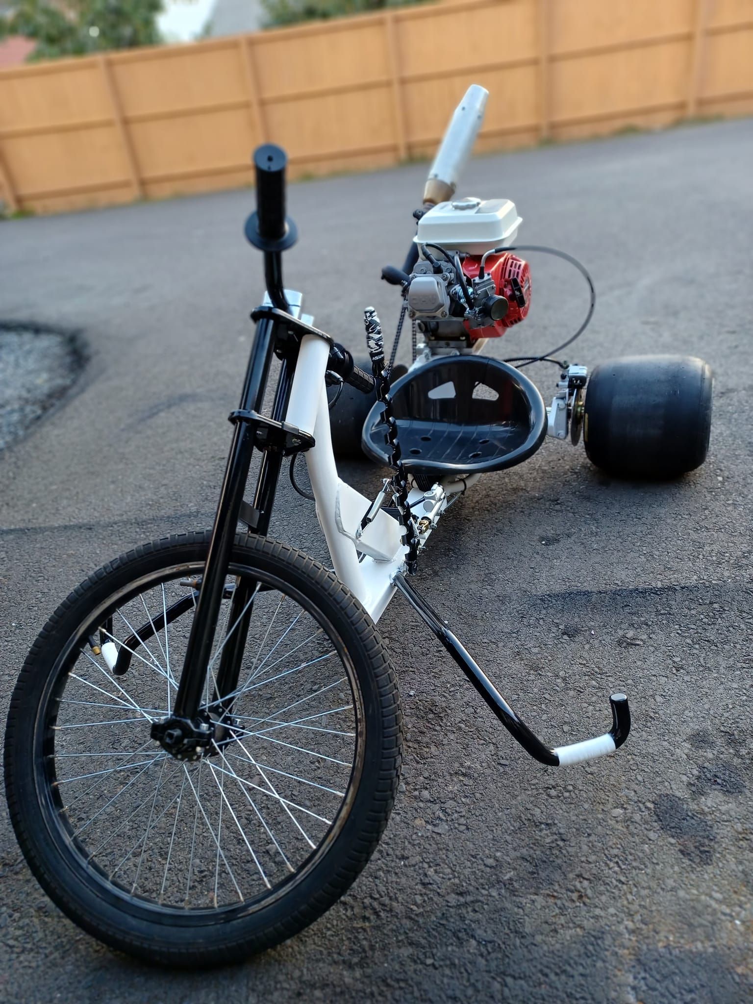 A bicycle with a motor attached to it is parked on the side of the road.