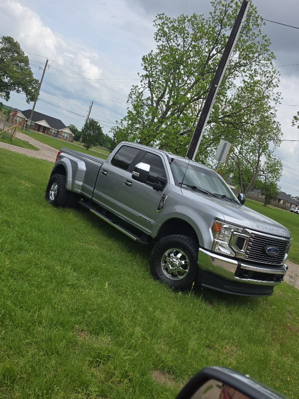 Silver pickup truck parked on grass beside a road under a cloudy sky