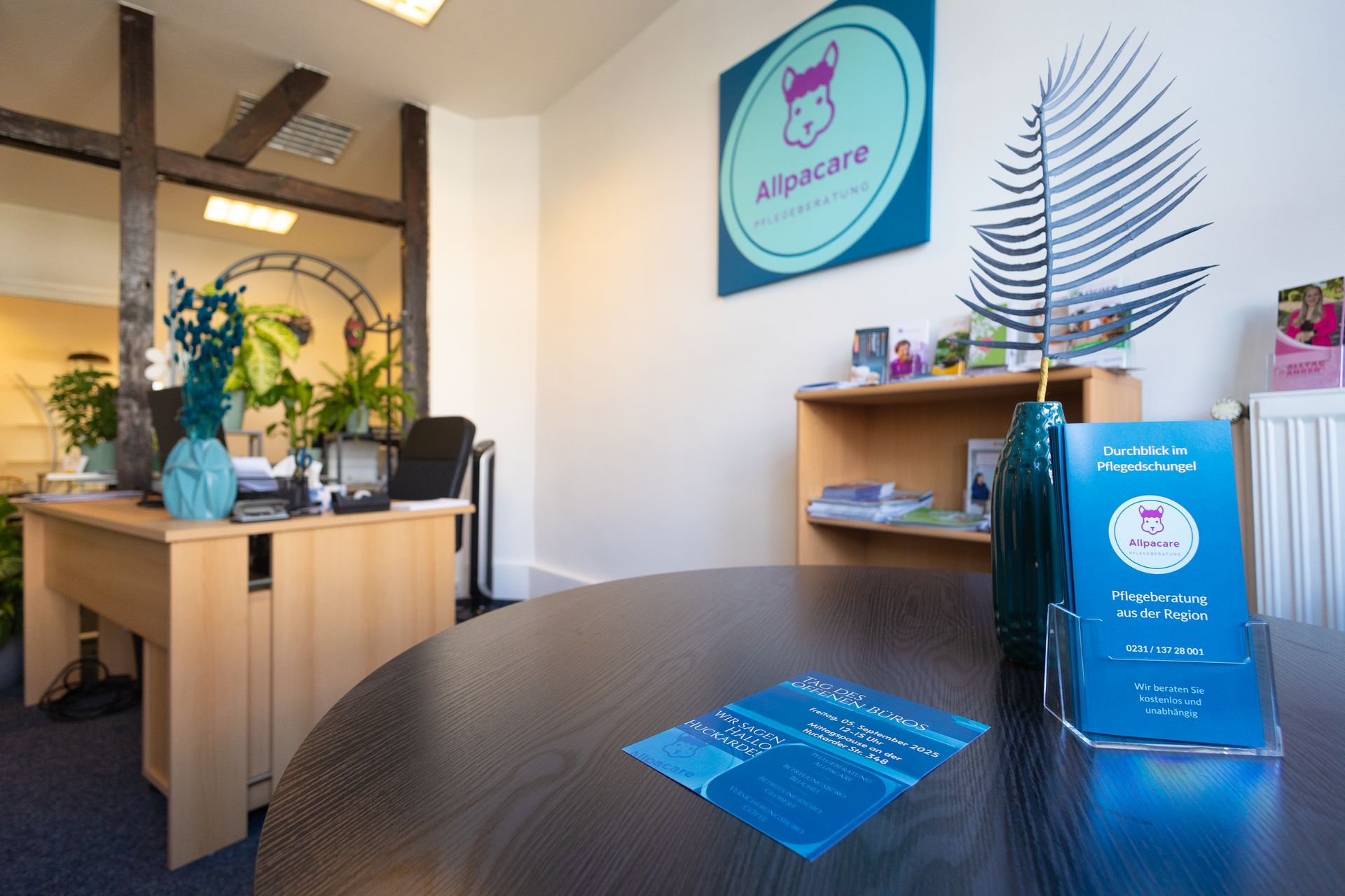 Allpacare Büro-Innenraum mit Beratungsplatz und Pflanzen
