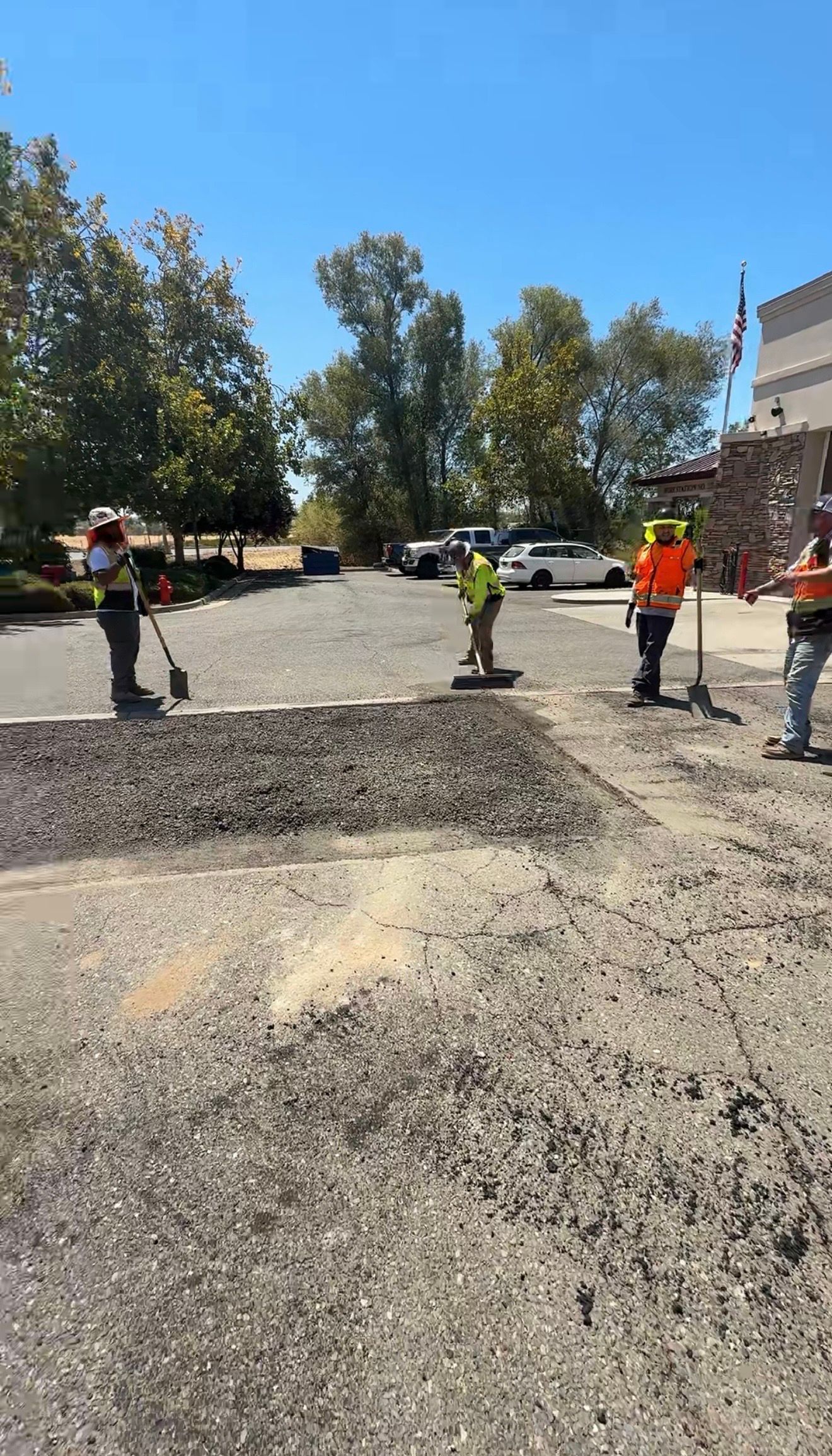 Road work crew in safety vests on a gravel street under a bright blue sky