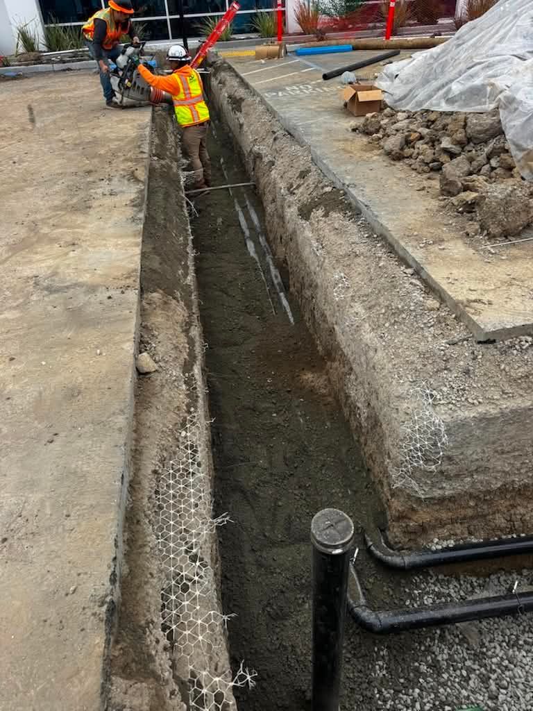Construction worker in neon vest working inside a narrow trench at a road site