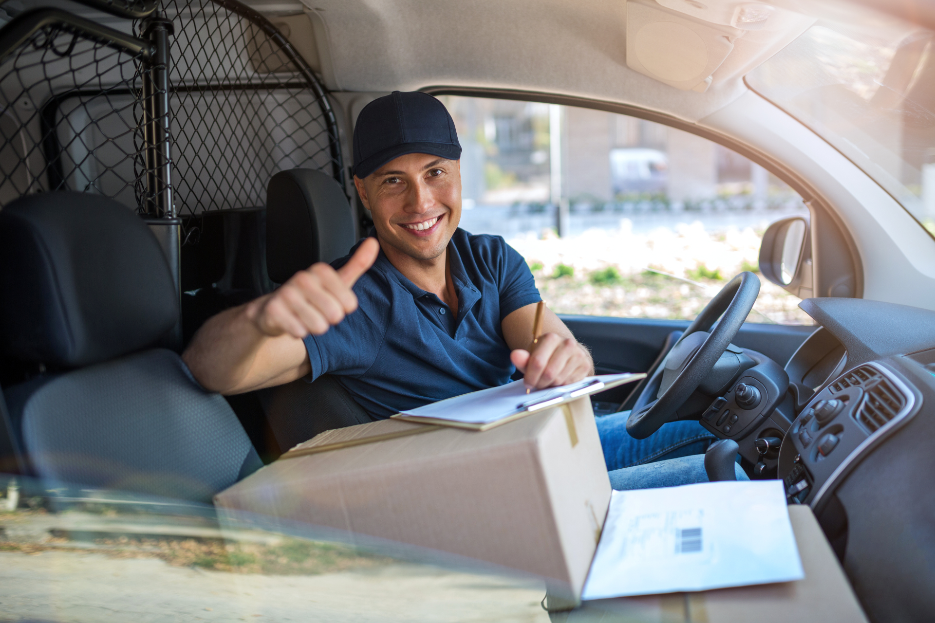 Delivery driver smiling in van, handing a package out the window